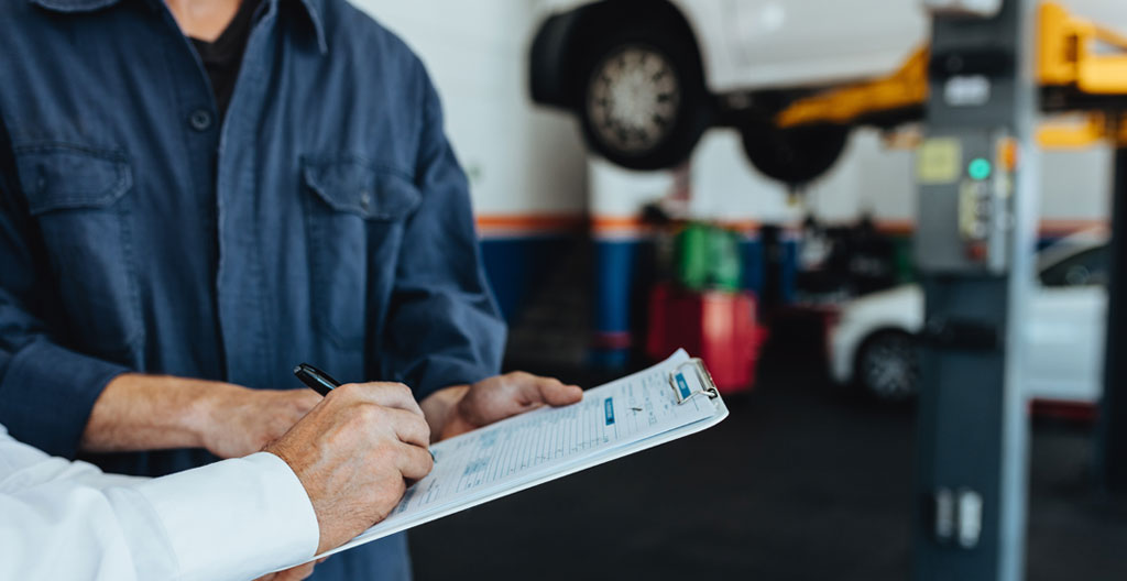 Carnet d'entretien automobile ouvert sur un bureau moderne lumineux avec tampons de révision visibles et factures de garage disposées à côté