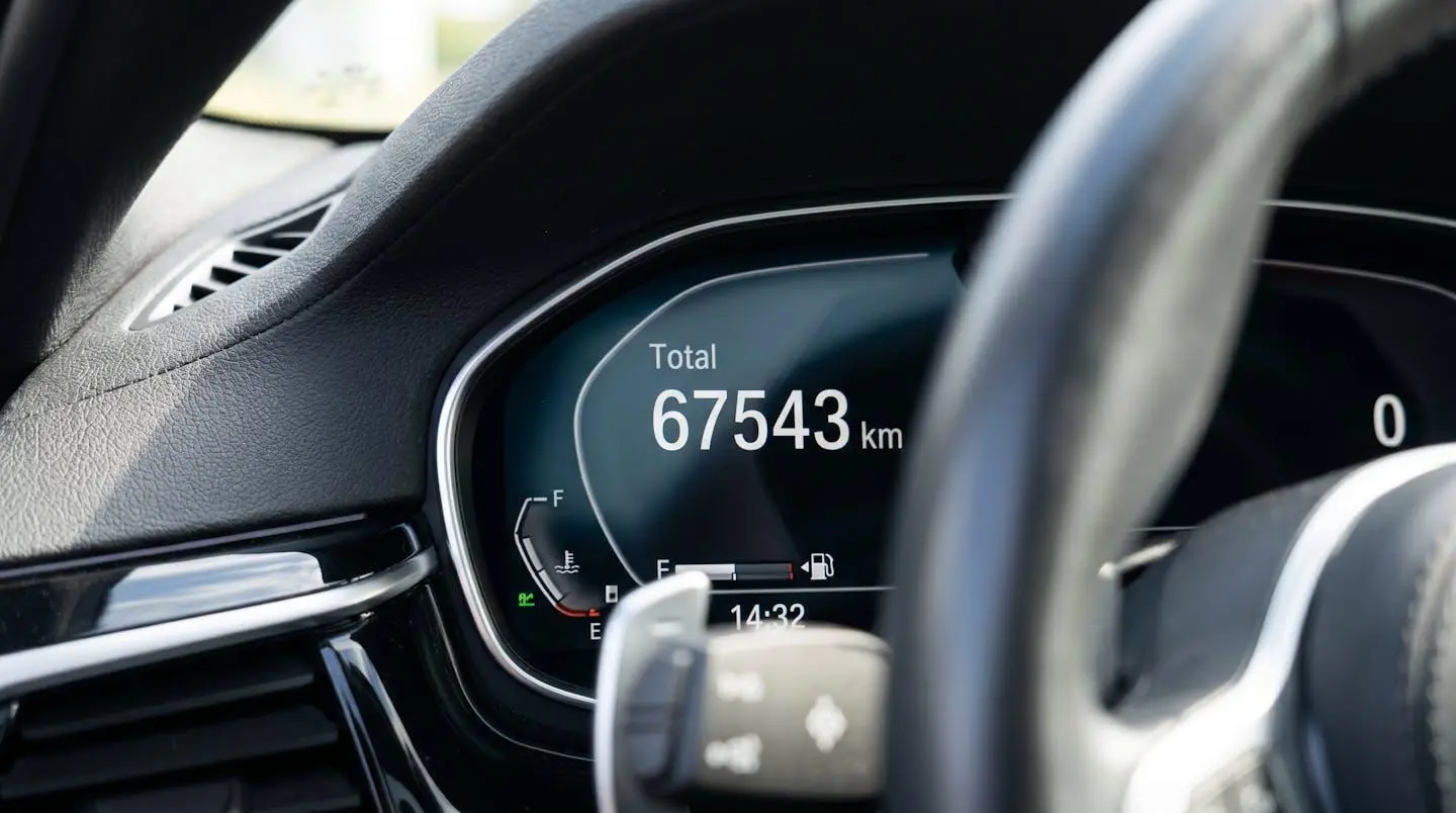 Gros plan sur un tableau de bord contemporain affichant un compteur numérique indiquant 67 543 kilomètres en chiffres blancs sur fond noir
